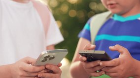 Kids boy girl play online games with phone in their hand on street. Modern technologies urban life. School children with backpack walk outdoors using smartphone. Children communicates using smartphone - Powered by Shutterstock - Get 15% off with code: PIKWIZARD15