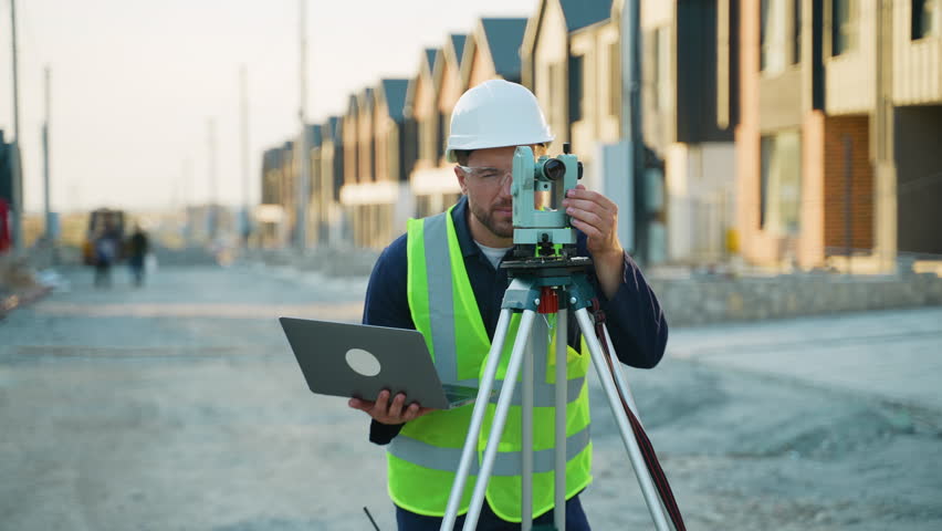 Surveyor engineer measuring land with theodolite on construction site