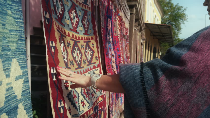 Young Woman Looks at Handmade Carpets with Colorful Patterns Unique to Anatolia