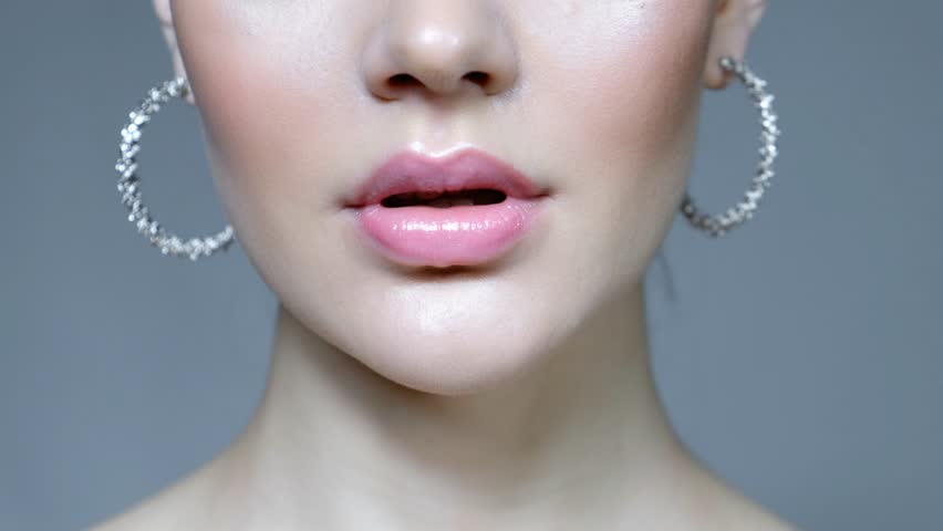 Closeup macro video of female lower part of face. Woman with lips with pink beauty lips makeup and earrings.