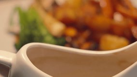 Focus Shift from Gravy Boat Jug to Sunday Roast Chicken Lunch with Hot Vegetables Broccoli, Parsnips, Carrots and Roast Potatoes. Classic British Cuisine Food. - Powered by Shutterstock - Get 15% off with code: PIKWIZARD15