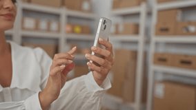 Woman holding smartphone with bare hands and tapping screen in storage building; concentration productivity. - Powered by Shutterstock - Get 15% off with code: PIKWIZARD15