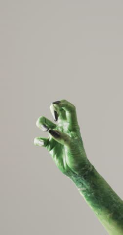 Vertical video of halloween green monster hand with copy space on grey background. Halloween, tradition and celebration concept.