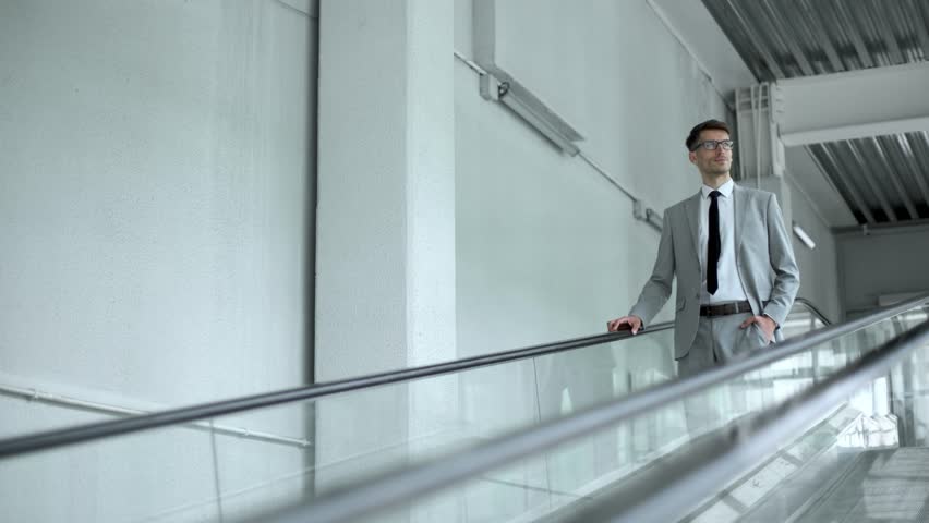 A man in a suit is walking down an escalator