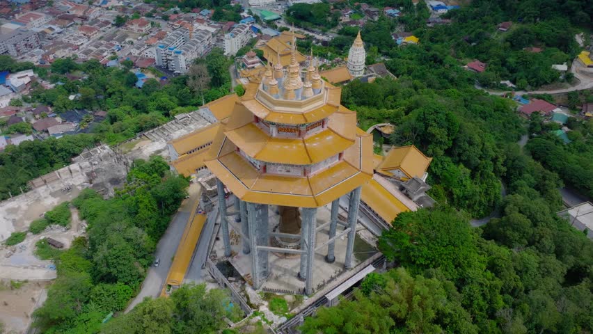 Drone footage over Kek Lok Si Temple in Penang, Malaysia, highlighting its golden pagoda roofs and detailed architecture with the city in the background.