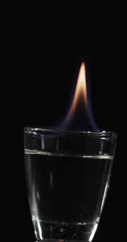 Vertical video of lit alcohol flames and copy space on black background. Fire, flames, heat and light concept.