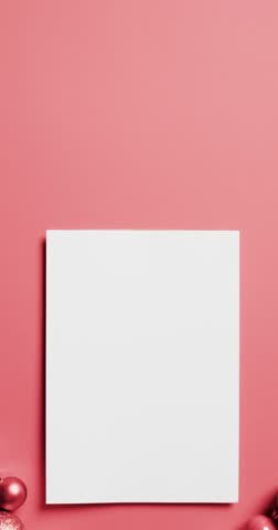 Vertical video of red baubles christmas decorations, white card with copy space on red background. Christmas, decorations, celebration and tradition concept.