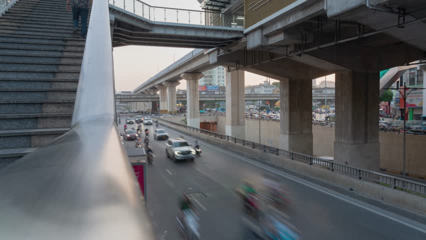 Street-level view of Hanoi’s elevated metro line and roadway with motion-blurred traffic below.