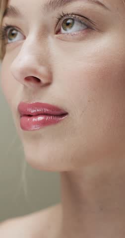 Vertical video of caucasian woman with blond hair touching face, copy space, slow motion. Health and beauty, make up, femininity concept, unaltered.