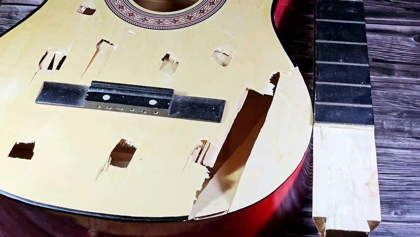 A broken wooden old classic guitar with damaged strings chords, shattered musical instrument, unattached damaged guitar with cut chord and wood, selective focus of non working music instrument