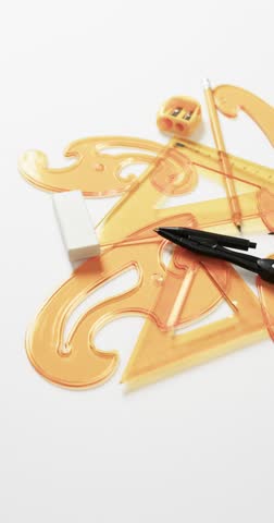 Vertical video of compass, pencil, sharpener, eraser and rulers on white background, slow motion. Geometry, design, learning and education concept.