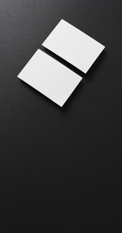 Vertical video of two white business cards arranged on black background, copy space, slow motion. Business, contact details, mock up, template for design.