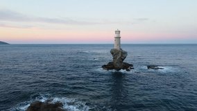 Tourlitis Lighthouse with spiral staircase on a rocky islet from the port of Chora at sunset, on Greek island of Andros, Aegean Sea, Drone shot - Powered by Shutterstock - Get 15% off with code: PIKWIZARD15