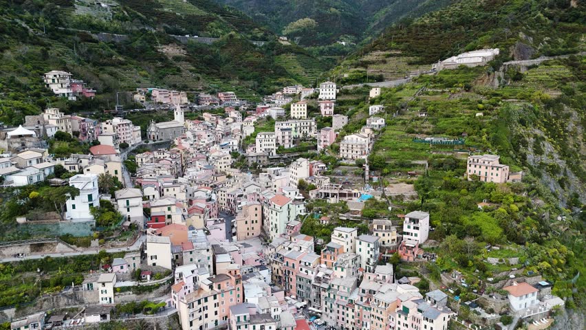 A cinematic retreat over Riomaggiore — pastel houses, cliffs, and waves blending in perfect harmony.