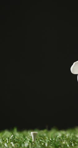 Vertical viedo of hand holding golf ball on grass and black background, copy space, slow motion. Golf, sport and hobby concept.