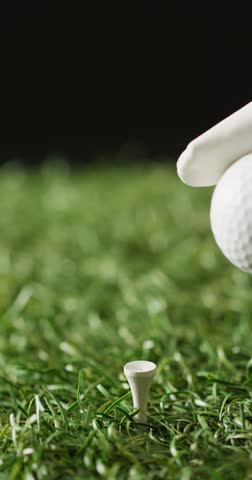 Vertical viedo of hand holding golf ball on grass and black background, copy space, slow motion. Golf, sport and hobby concept.