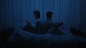 A couple sits back to back in bed, both illuminated by the glow of their smartphone screens. Addiction to gadgets and social media, digital isolation, relationship alienation, and technology overuse. - Powered by Shutterstock - Get 15% off with code: PIKWIZARD15