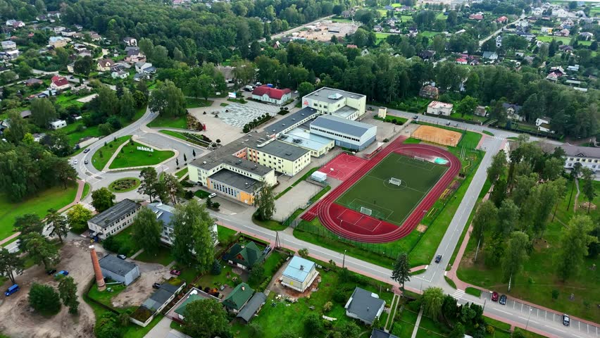 Aerial view of a school campus with a stadium and running track in Ikskile