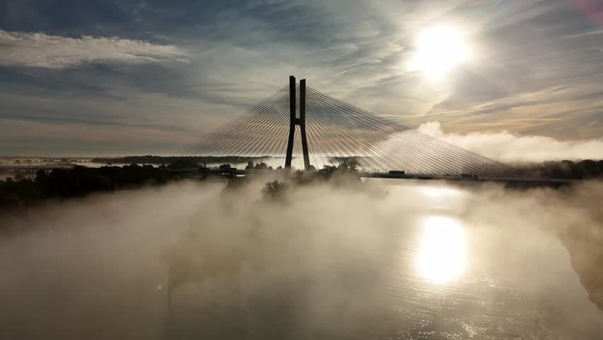 Aerial view of Redzin Bridge (Most Rędziński) in Wroclaw, Poland, surrounded by morning fog and forest under dramatic sunrise sky – scenic drone landscape of autumn mist and architecture