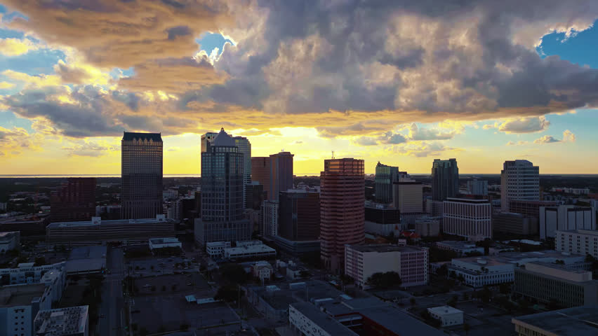 The evening sun has set in downtown Tampa with dramatic clouds glowing in the sky and casts warm light on buildings.