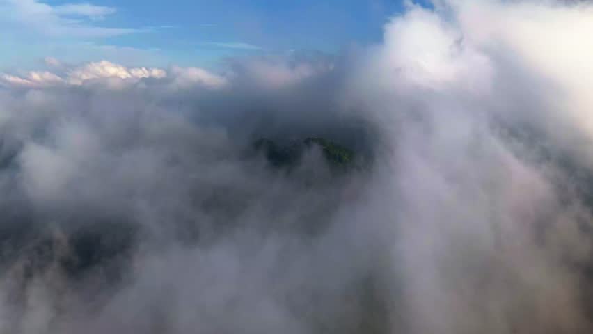 Aerial view of thick, ethereal clouds partially obscuring lush green vegetation, creating a mystical and serene landscape, Yogyakarta, Daerah Istimewa Yogyakarta, Indonesia.