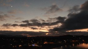 Serene Night Aerial View of a Coastal Town Harbor at Dusk, with Crescent Moon, Orange Sky, and Twinkling City Lights - Powered by Shutterstock - Get 15% off with code: PIKWIZARD15