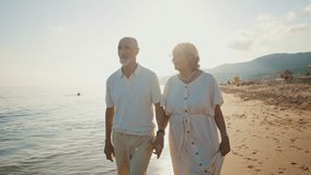 Happy senior couple walking hand in hand along the seashore at sunset, the woman showing the man a beautiful seashell she found, enjoying their retirement and creating romantic memories together - Powered by Shutterstock - Get 15% off with code: PIKWIZARD15