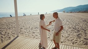 Happy senior couple lovingly dancing on a wooden walkway at the beach. Cheerful elderly partners enjoying their retirement together, spending a sunny summer day by the seaside with a smile - Powered by Shutterstock - Get 15% off with code: PIKWIZARD15