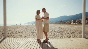 Happy senior couple lovingly dancing on a wooden walkway at the beach. Cheerful elderly partners enjoying their retirement together, spending a sunny summer day by the seaside with a smile - Powered by Shutterstock - Get 15% off with code: PIKWIZARD15