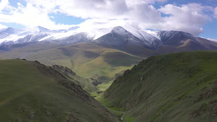 Sunny day aerial view of river valley in mongolia's altai mountin region with snowed mountains in the background on a sunny day