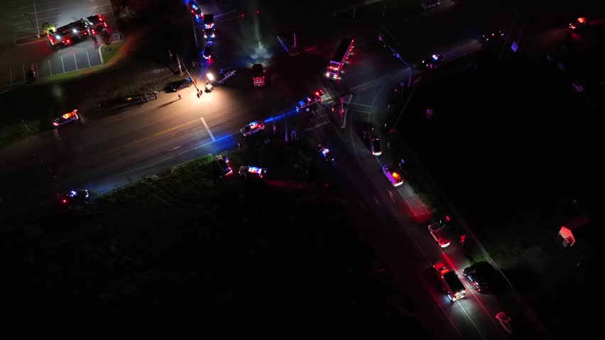 Accident scene at night with flashing blue and red lights of emergency vehicles. Aerial top down shot. Several police cars and ambulance cars.