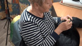 Grandma sews by hand with a thread and a needle. An elderly woman repairs clothes. Sewing needlework by old hands. - Powered by Shutterstock - Get 15% off with code: PIKWIZARD15