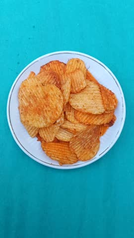 A plate of potato chips. The chips are crispy and golden, making for a popular snack choice. They fall into the categories of fast food and junk food.