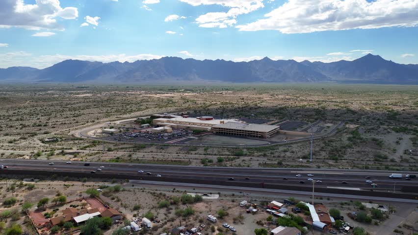 Aerial view of Vee Quiva Casino and parking lots surrounded by desert landscape, under a blue sky with white clouds, South Komatke Lane, Arizona, United States.