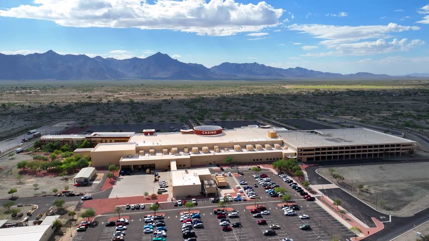 Aerial view of Vee Quiva Casino, its beige architecture contrasting with the surrounding desert and distant mountains under a bright sky, Laveen Village, Arizona, United States.