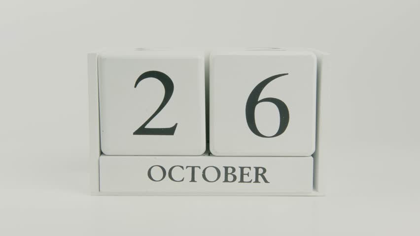 Hand flips a wooden white calendar, changing the date from October 26 to 27, on a clean white background. Perfect for time, schedule, and holiday concepts