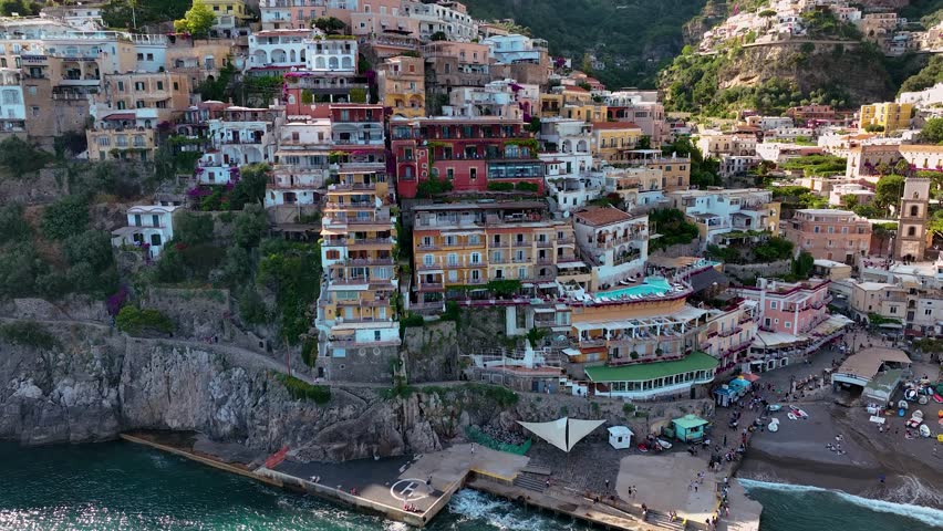 Aerial view of vibrant buildings cascading down to the beach, contrasting with the sea, creating a picturesque scene, Positano, Campania, Italy.