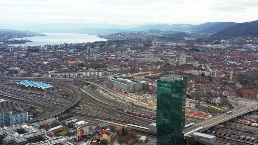 Aerial view of the sprawling cityscape featuring Zurich HB and the towering Prime Tower, with a backdrop of mountains, Zurich, Zurich, Switzerland.