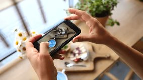 Young food blogger taking a picture of a healthy breakfast with blue latte and dessert for social media. Close up of hands holding a mobile phone and capturing content in a cafe setting - Powered by Shutterstock - Get 15% off with code: PIKWIZARD15