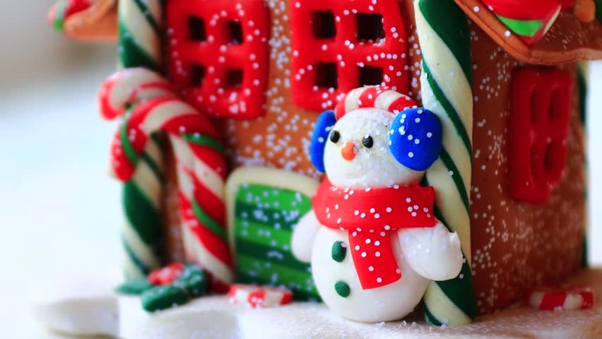 A small, intricately designed gingerbread house with a cheerful snowman on top, perfect for winter or holiday-themed projects.