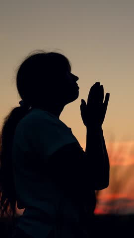 Faith in God. Close-up of Christian woman praying at sunset. Girl against skyline in sun, praying to God for her family children. Woman Relaxation meditation in nature. Faith, Hope, Love. Silhouette