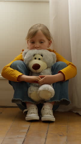Lonely sad little Caucasian girl child kid sitting on floor at home suffering domestic violence family problem hugging teddy bear toy divorce worried daughter feeling despair custody adopt trouble