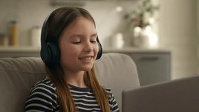 Active happy Caucasian little girl child kid daughter in headphones listening music with laptop computer technology enjoy audio song listen dancing moving sitting on couch dance smiling having fun joy - Powered by Shutterstock - Get 15% off with code: PIKWIZARD15
