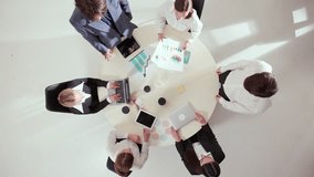 Top view of diverse business team discussing charts and laptops around round meeting table. Concept of collaboration, leadership, financial planning, and focused teamwork with analytical emotion. - Powered by Shutterstock - Get 15% off with code: PIKWIZARD15