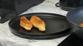 A hand adds a third golden pie from the pan onto a plate with two others, steaming and crispy, creating a warm homemade food scene. - Powered by Shutterstock - Get 15% off with code: PIKWIZARD15