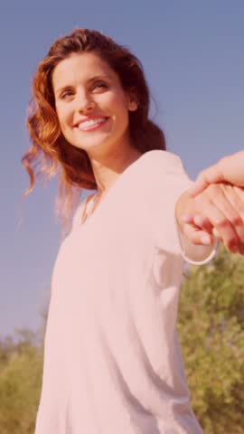 Animation of red heart balloons floating over couple in love holding hands in summer. Happy Valentines Day celebration concept digitally generated image.
