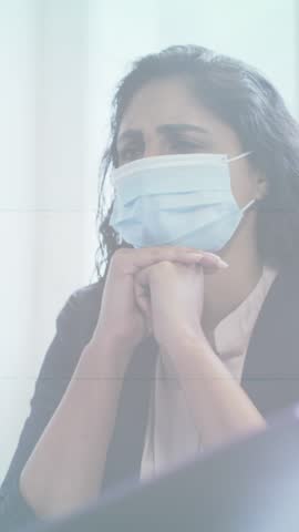 Stop sign over covid-19 cells moving against thoughtful woman wearing face mask at office. coronavirus covid-19 pandemic concept