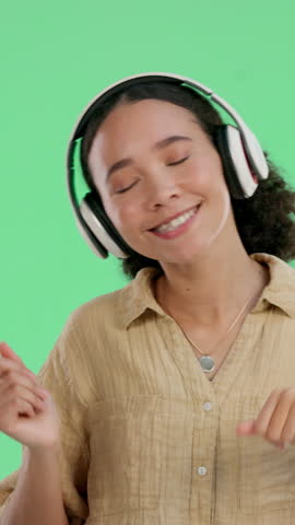 Headphones, dancing and woman by green screen listening to music, radio or playlist with energy. Happy, audio tech and female person streaming album or song for party with rhythm for entertainment.