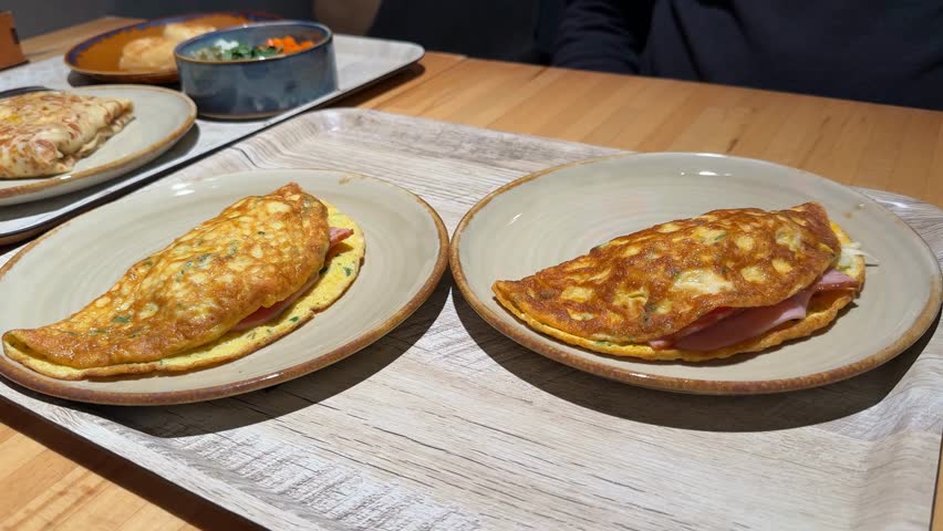 Breakfast omelettes with cheese and ham served on wooden trays in a cozy dining setting video