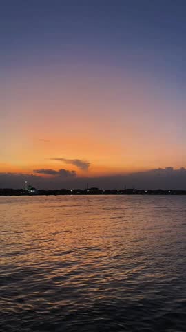 Dramatic Sunset Gradient Over Water with City Skyline Silhouette